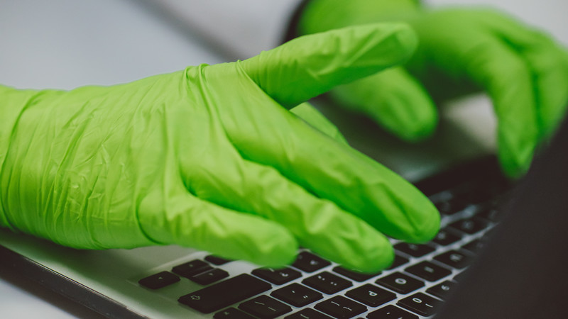 Green gloves typing on laptop